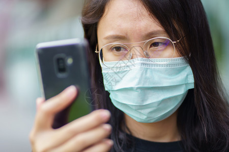 户外戴口罩看手机的妇女图片