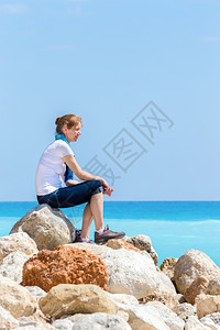 夏天欧洲妇女坐在近海岸岩石上的欧洲妇女海洋希腊图片