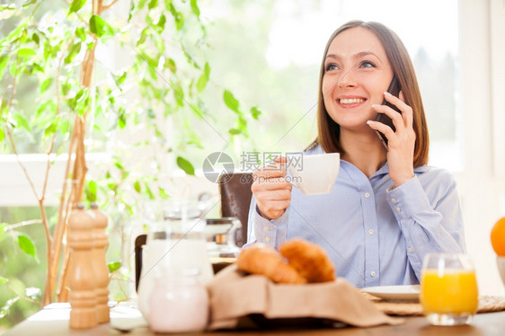 移动的正式优雅相片中黑发女商人在吃早餐时打来电话图片
