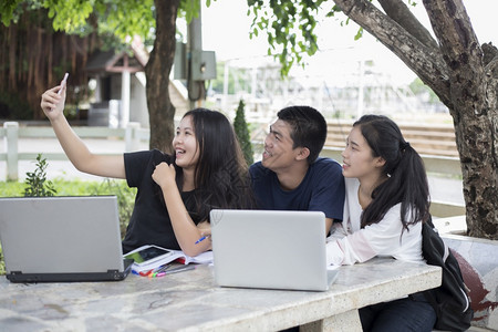 肖像药片团体亚洲集学生使用平板和笔记本分享校园草坪工作的想法与朋友一起微笑自拍在校园草坪上工作图片