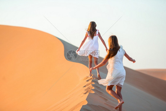 阳光在阿拉伯联合酋长国RubalKhali沙漠的丘中女童与之间度假的小女孩生态们图片