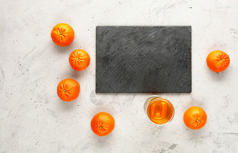 石板由灰白制成的切割周围环绕着黑桃橙子水果这些实随机地放在附近的灰色混凝土背景上复制灰蓝板的空间切割它位于灰红混凝土背景上整个橘图片
