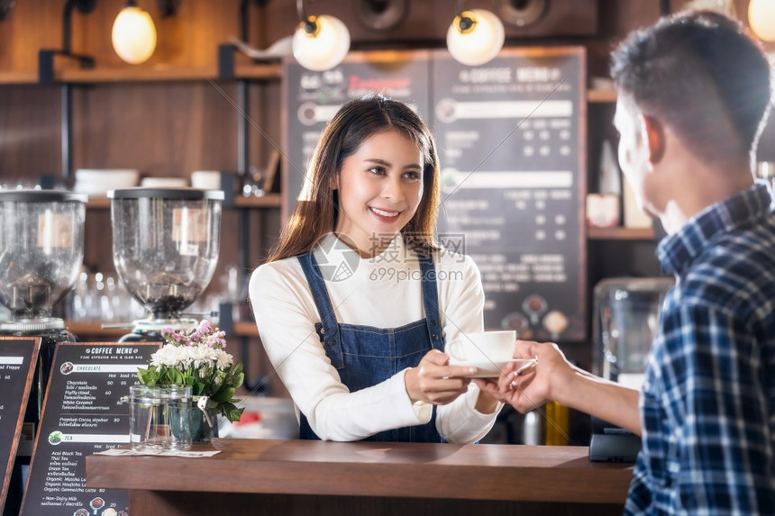喝牛奶亚洲小企业主律师协会在咖啡店柜台向青年顾客提供一杯咖啡小商业主和咖啡店餐馆的创办人概念小型商业主亚洲协会为咖啡店和餐馆的年图片