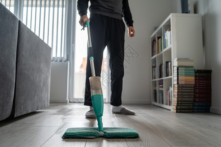 男丈夫在家做务房间里擦木板或压层地白天保持卫生清洁消毒客厅在拖把