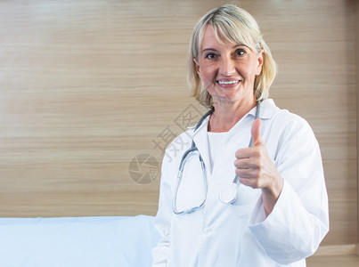 保护的预防一名天主教高级女医生的肖像她站立在医院时手持听诊器微笑和大拇指白色的图片