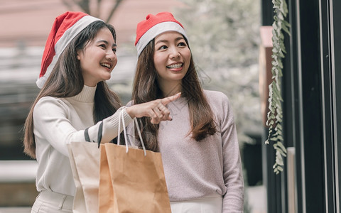 在圣诞节新年庆典和销售折扣概念中两个可爱的妇女在百货店买窗户时拿着袋子在圣诞季新年庆祝和销售折扣概念女孩们服装顾客图片