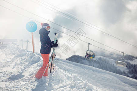 寒冷的极端年轻女滑雪者站在斜坡山丘和背景为SochiKrasnayaPolyana的椅子上闲暇图片