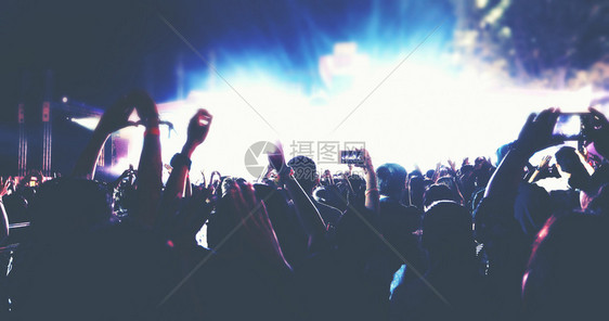 扇子提高明亮的舞台灯下举起手来在音乐会观众看节日人群的后视线上娱乐图片