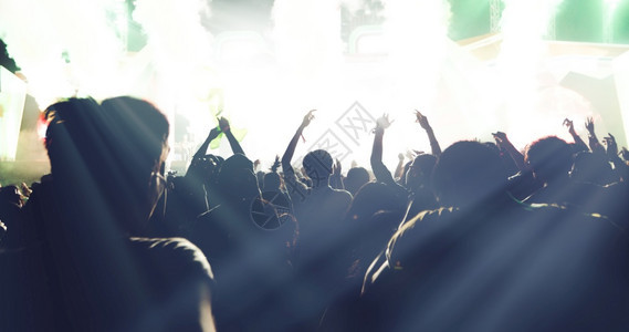 剪影明亮的舞台灯下举起手来在音乐会观众看节日人群的后视线上夜生活乐趣图片