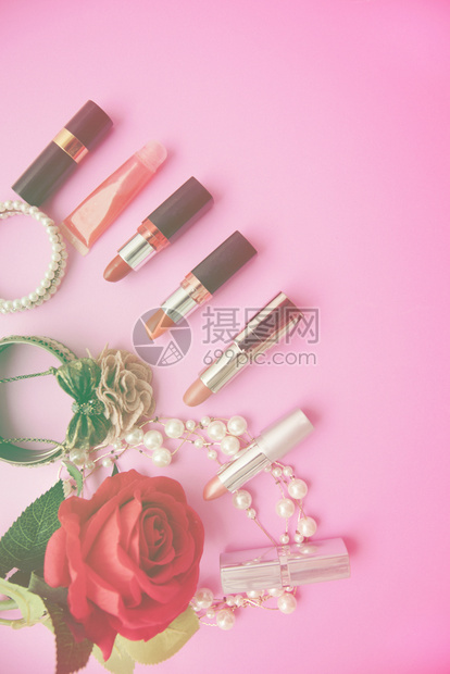 奢华产品粉红色背景的顶端观光色由彩口红珍珠和鲜花组成的装饰平面涂抹器图片