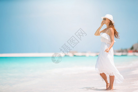 脚年轻美丽的女人穿着白色衣服在热带海滨年轻美丽的女士在热带海边玩得开心快乐女孩在蓝天空和海中绿水的下盘背景上过着快乐的热带海边摆图片