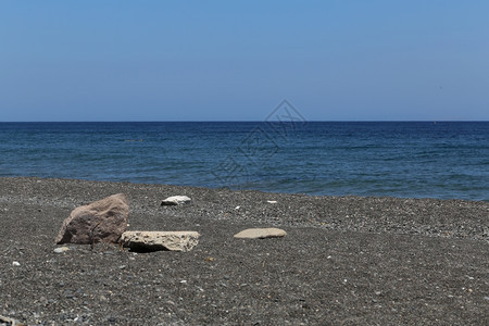 希腊圣托里尼岛的卡马海滩带有黑色火山石水娱乐松弛图片