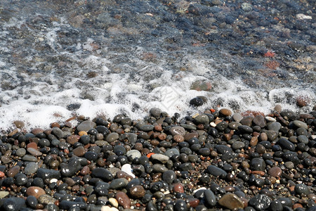 水浪漫的闲暇希腊圣托里尼岛的卡马海滩带有黑色火山石背景图片