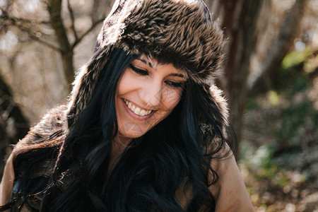 年轻有魅力微笑着戴俄罗斯皮制手帽子的年轻女森林户外有趣的图片