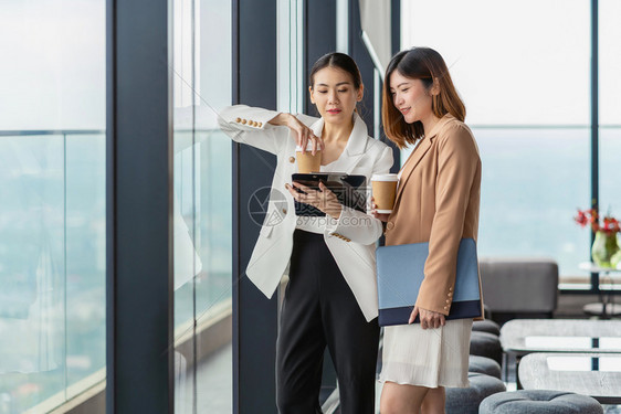 对话或者合伙在现代办公室或合用空间的咖啡休息期有两名亚洲女商人在咖啡休息下班后放松和谈话商业人员伙伴关系概念时发言图片
