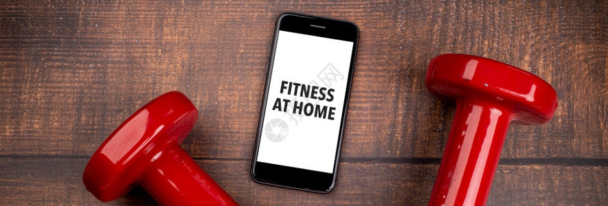 普拉提屏幕教练员用于培训室内在线健身方案的红哑铃和智能手机木林背景App用于培训室内在线健身方案家庭在线锻炼TopViewCov图片