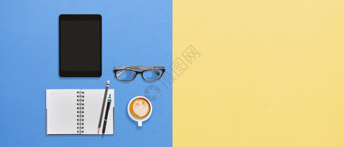 现代办公室台式楼寓提供工作空间生活方式用平板笔本眼镜和一杯热咖啡混合饮料供应创造颜色黄的蓝背景及复制版面最小的笔记本角度图片