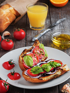 番茄新鲜三明治包面西红柿蔬菜和橄榄油素食三明治的原料玻璃杯中鲜嫩挤制的柑橘汁黑生木本底以及法语早餐图片