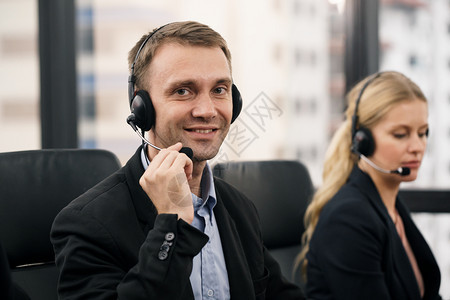 代理人接触商业坐在客户服务部办公室的一位笑着微英俊男子有在呼叫中心工作的耳机图片
