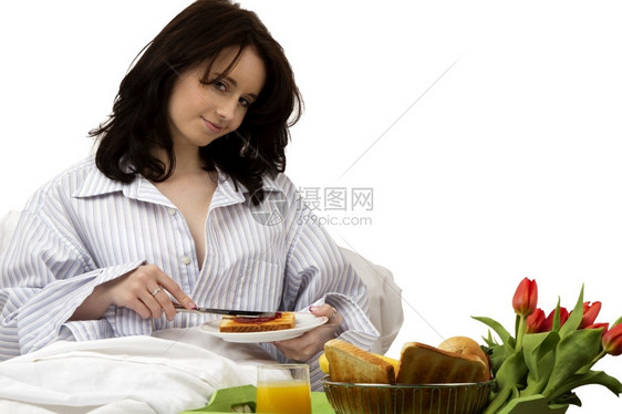 食物单身的女士年轻人在床上吃早餐年轻女人在床上吃早餐三明治上涂果酱图片