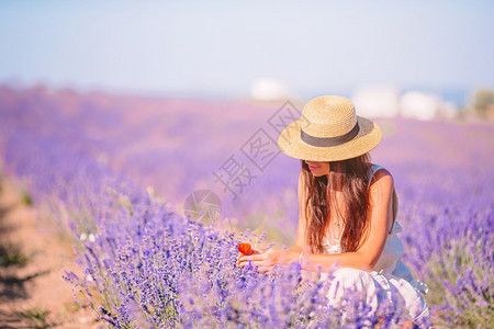 花的穿紫衣年轻美女穿着白裙子和帽日落时戴白帽子的紫花朵丰富多彩的夏天图片