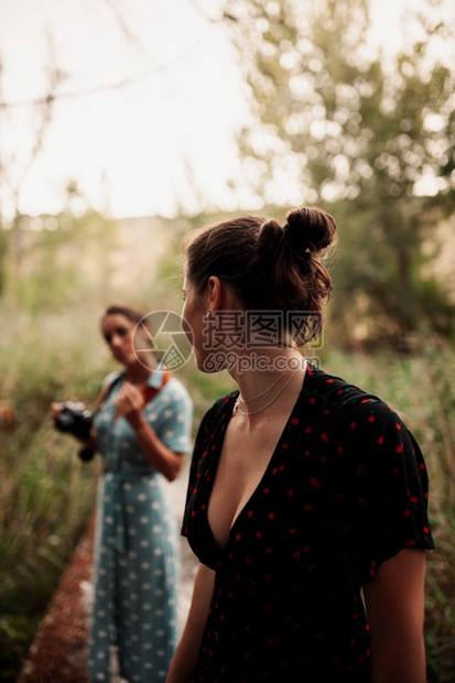 现代的年轻两个女子在森林里拍相照身穿礼服和运动鞋的树上拍照白天图片