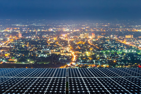 绿色建筑物夜晚太阳能电池板或光伏组件太阳能发电站夜间市中心背景照耀城市中心风景的太阳能电站替代源概念在夜间使用图片