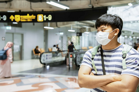 亚洲人佩戴外科假面罩用跨越的手臂站在上用于旅行技术导航者Gps连接生活方式假日旅行共冠19个概念方向联系数字的图片