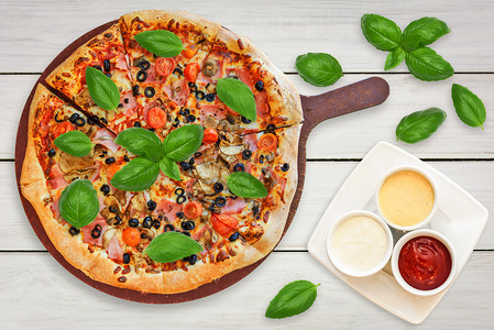 餐饮所有的以火腿蘑菇樱桃西红柿莫扎里拉黑橄榄为首的意大利传统比萨饼配有烧焦叶和酱汁番茄图片
