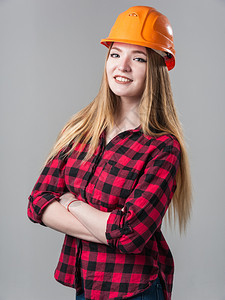 女孩巴斯塔建筑师一个年轻有魅力的女人金发橙色头盔格子衬衫中灰色背景一个年轻有魅力的女人中灰色背景图片