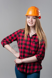 吸引人的一个年轻有魅力的女人金发橙色头盔格子衬衫中灰色背景一个年轻有魅力的女人中灰色背景工人员图片