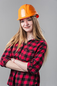一个年轻有魅力的女人金发橙色头盔格子衬衫中灰色背景一个年轻有魅力的女人中灰色背景美丽的年轻安全帽图片