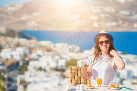 美女在户外咖啡厅吃早饭风景令人惊艳女孩清晨享受热咖啡美丽的女士在户外咖啡厅吃早餐风景令人惊叹海热的希腊图片