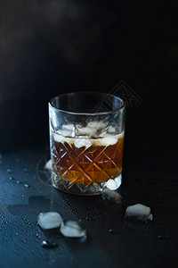 金的波旁酒滗水器一杯威士忌或波旁在黑石桌上加冰一杯的威士忌和一个方形醒酒器一杯苏格兰威士忌和冰图片