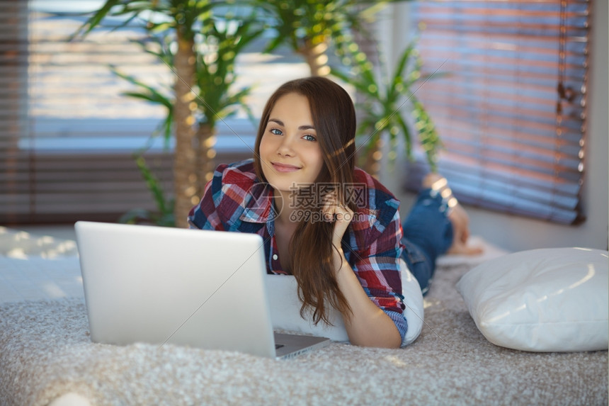 工作互联网年轻女人躺在沙发上网冲浪室内图片
