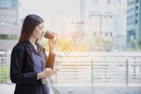 外部使用智能手机在线购物打电话发短信互联网技术生活方式的女商人使用手机在城市街道上行走智能手机自信女现代城市企业家微笑图片