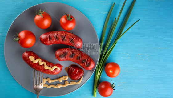 蓝木板传统食物的香肠概念红番茄和在叉子上的营养香肠在盘子上扎起的营养香肠概念红番茄白色的吃营养图片