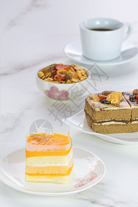 巧克力干净的正方形橙色软蛋糕咖啡和在垂直框中大理石桌面上带有黑咖啡的塔布有选择地聚焦图片
