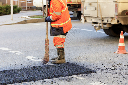 等级黑色的活动道路施工人员在修好的路段上用木头水平整新鲜沥青筑路工人在部分道上收集新鲜沥青并将其平整以便在道路施工中进行维修图片