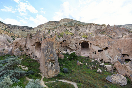 旅游在开阔蓝天下古老的红沙石城在卡帕多西亚安蒂克市锥脊背景的山谷内巨大居民洞穴和山红色河谷卡帕多西亚的住宅洞穴以及Capadoc图片