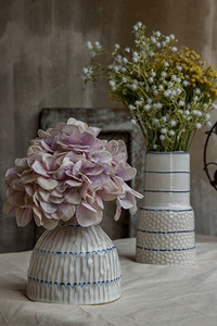 质地海报优的两块白色手工制陶瓷花瓶中的束放在白纸桌布上的色手制陶瓷花瓶上在阳台房子的装饰中用旧水泥墙挂着有选择地聚焦图片