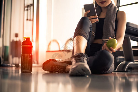 健康蛋白质保持女在健身房锻炼时使用智能手机和拿着苹果的特写运动和技术概念生活方式和医疗保健主题图片