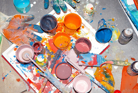 油漆木制的艺术家不同罐头和杯子中混合的多彩涂料绘画员配额工具在不同罐子和杯中混合的刷乌紫色涂料画家配额工具图片