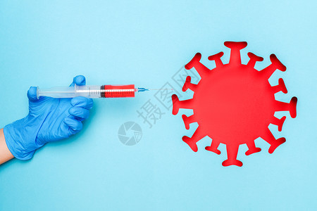 手握乳胶套注射器装有疫苗药物和抽象的红色冠状细菌微生物蓝色背景概念疫苗接种和传染病流行Covid19手握乳胶套注射器装有疫苗药物图片