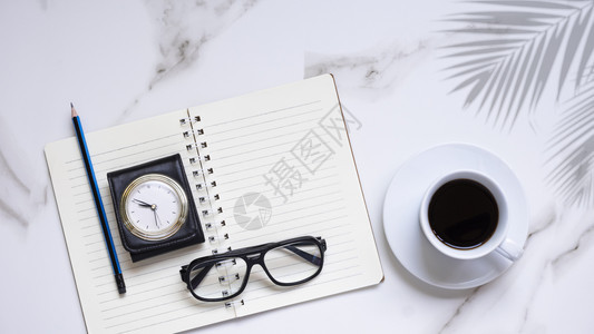 白陶瓷杯眼镜老式皮革盒手表带螺旋笔纸的铅和白色大理石板上的棕榈叶阴影中黑咖啡平面DSCF5427放松热的休息图片