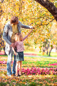 快乐的父亲和女儿在秋天公园共聚一堂父亲和孩子的家在美丽秋天公园中爸和孩子的家他母亲图片