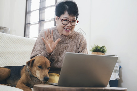 老的亚洲高龄女在笔记本电脑上进行视频呼叫在屏幕上挥手与远距离人士在网上聊天请享用在线的图片