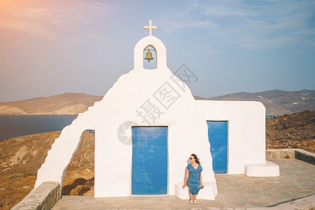 希腊Mykonos岛的年轻女子和传统白色教堂希腊Greek岛的蓝门女青年和传统白色教堂希腊Mykonos岛的海洋观循环吸引力图片