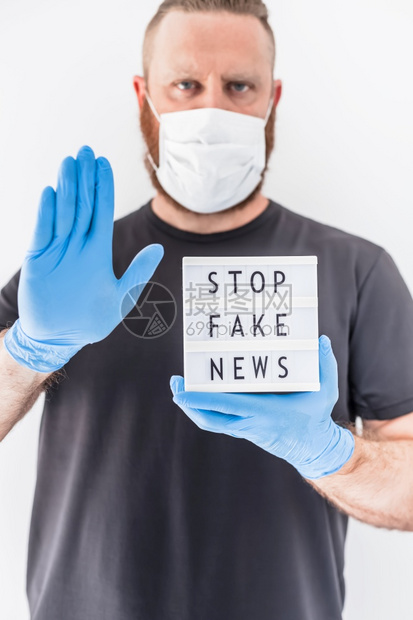 传播虚假信息误导在Covid19大流行病概念期间的假新闻涂戴防护面具和医疗手套的人举着带短信的灯箱停止假消息人们想知道有关冠状的图片