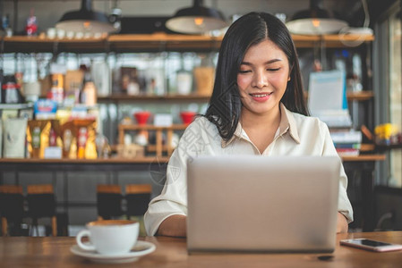 在室内亚洲女自由职业者在咖啡馆使用笔记本电脑时微笑与成功概念商业和成功概念咖啡店和户外主题食堂背景店铺阅读图片